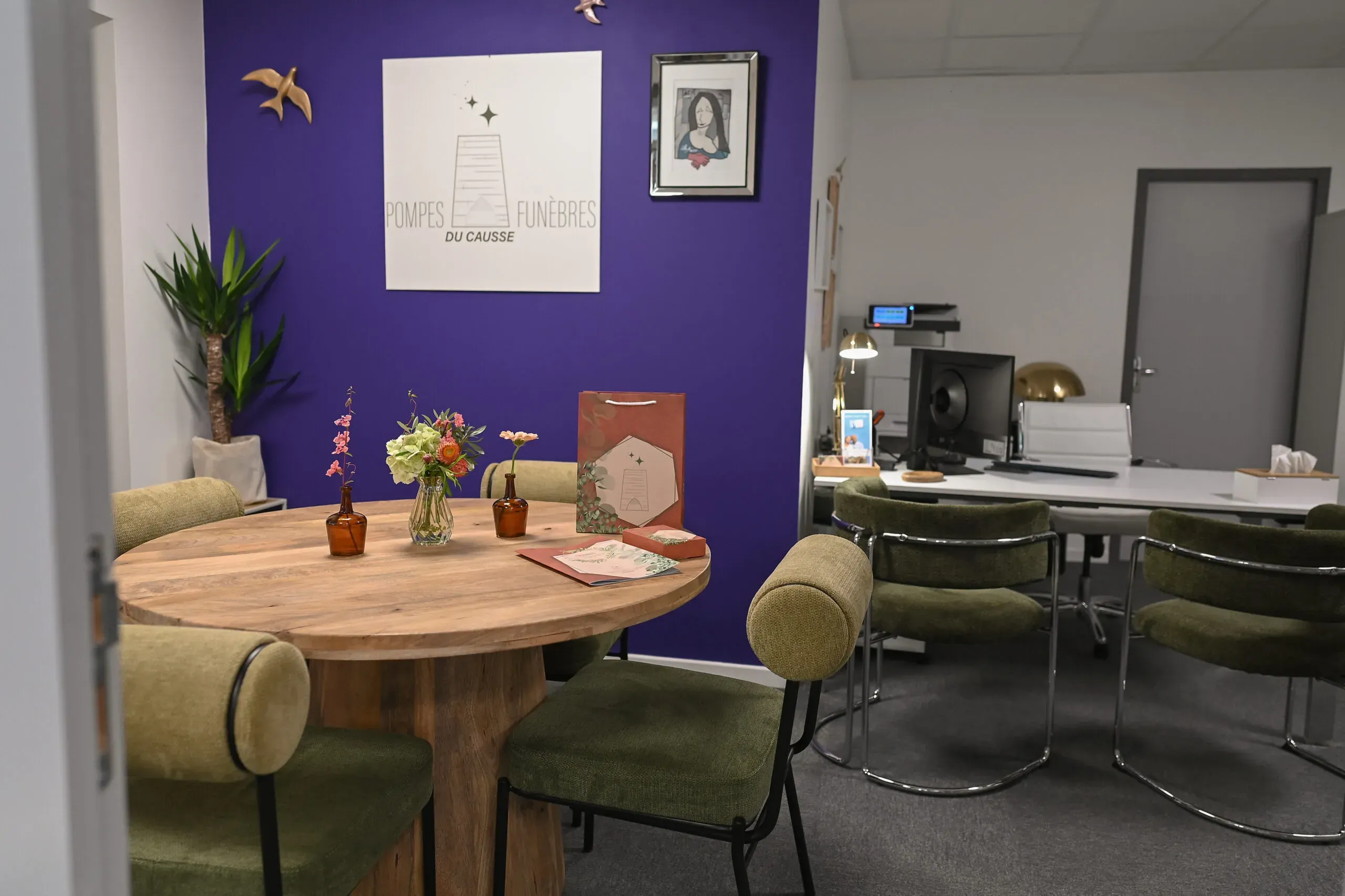 Espace d'accueil des Pompes Funèbres du Causse avec mur violet et table ronde