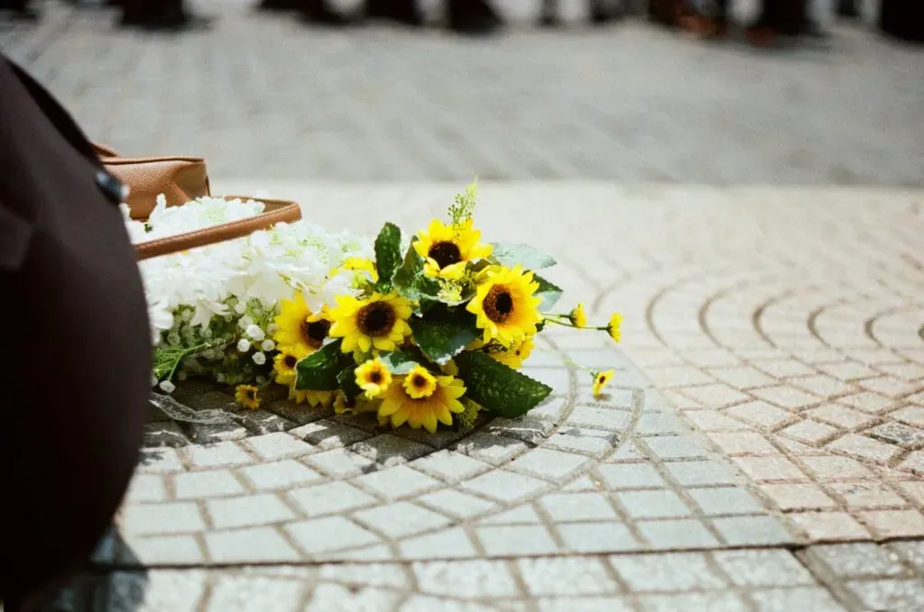 Bouquet de tournesols et fleurs blanches posé sur un sol pavé