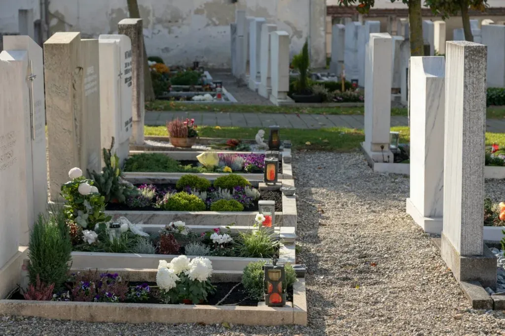 Tombes alignées et fleuries le long d'une allée gravillonnée de cimetière