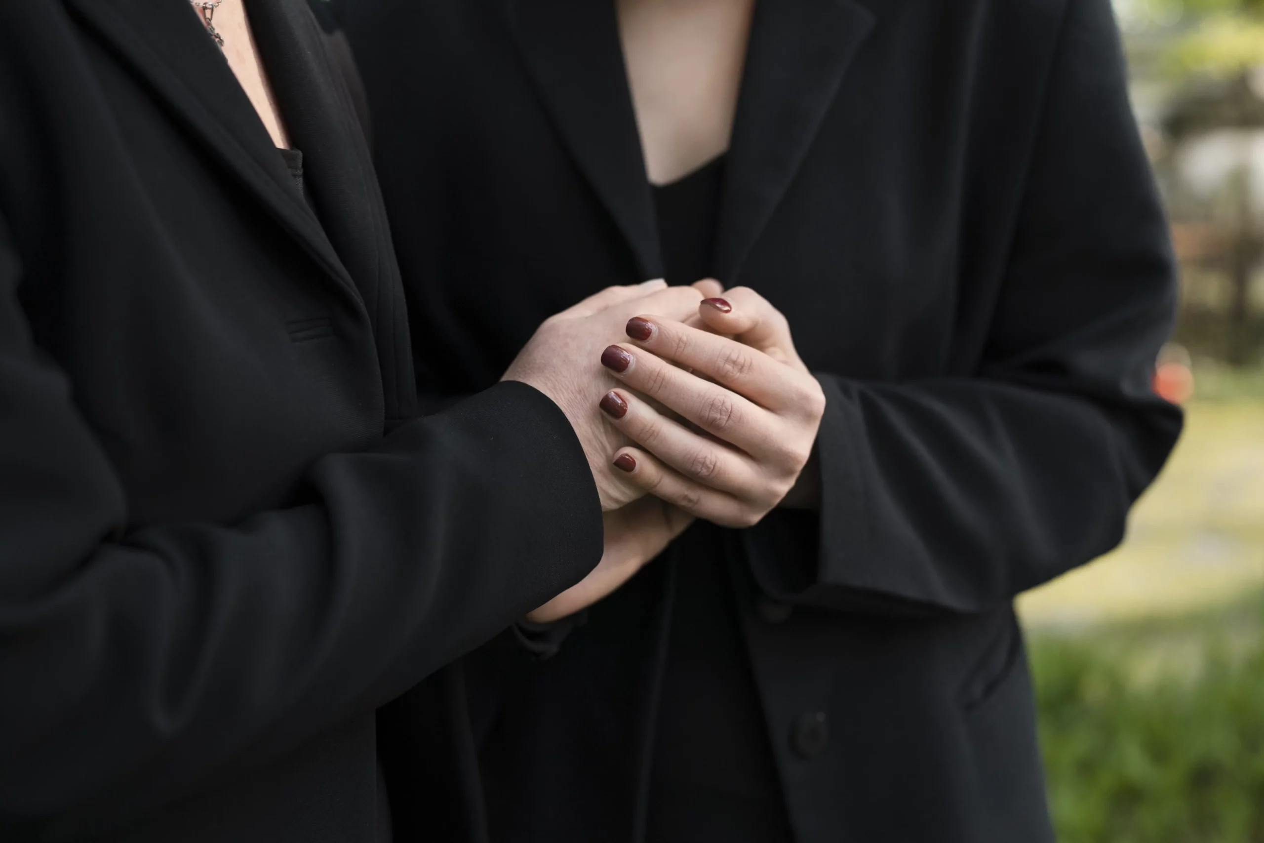Gestes de soutien et de condoléances entre proches vêtus de noir.